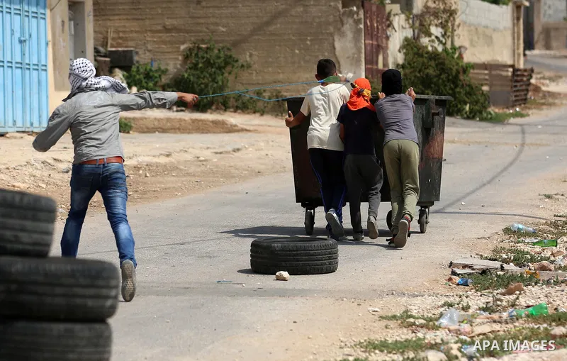 A Palestinian protester uses a slingshot to hurl stones towards Israeli forces during clashes following a weekly demonstration against the expropriation of Palestinian land by Israel in the village of Kfar Qaddum, near t...