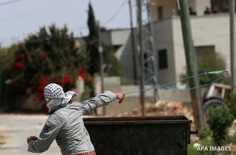 A Palestinian protester uses a slingshot to hurl stones towards Israeli forces during clashes following a weekly demonstration against the expropriation of Palestinian land by Israel in the village of Kfar Qaddum, near t...