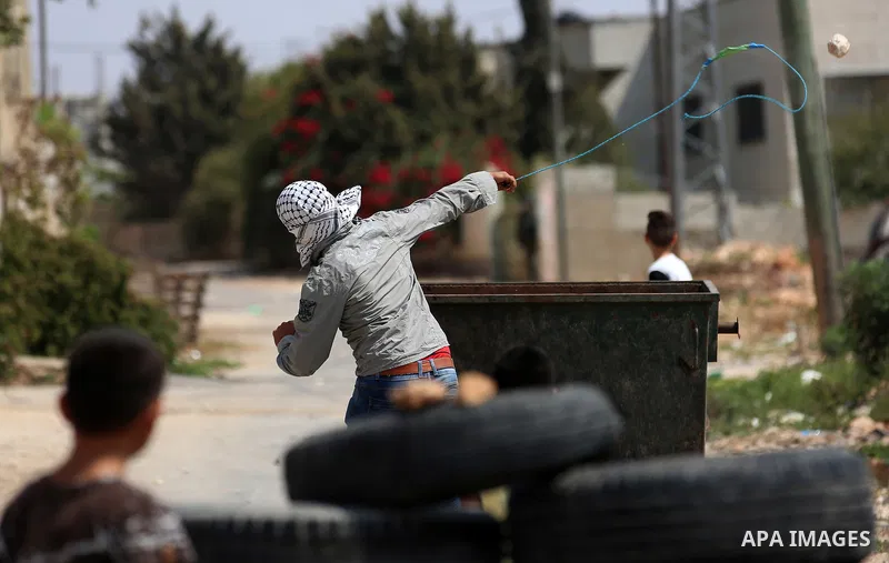 A Palestinian protester uses a slingshot to hurl stones towards Israeli forces during clashes following a weekly demonstration against the expropriation of Palestinian land by Israel in the village of Kfar Qaddum, near t...