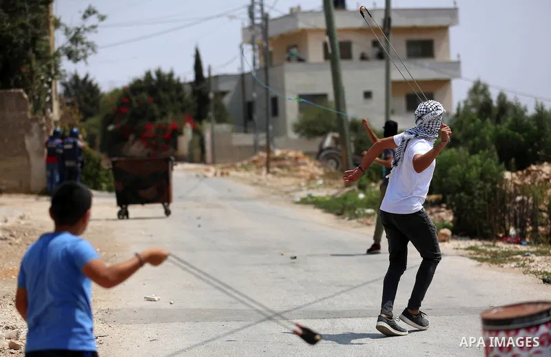 A Palestinian protester uses a slingshot to hurl stones towards Israeli forces during clashes following a weekly demonstration against the expropriation of Palestinian land by Israel in the village of Kfar Qaddum, near t...