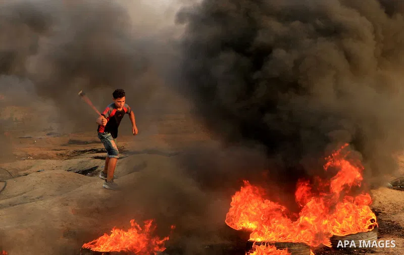 Palestinian protesters gather during clashes with Israeli troops in tents protest where Palestinians demand the right to return to their homeland at the Israel-Gaza border, in al-Bureij in the center of Gaza Strip on Aug...