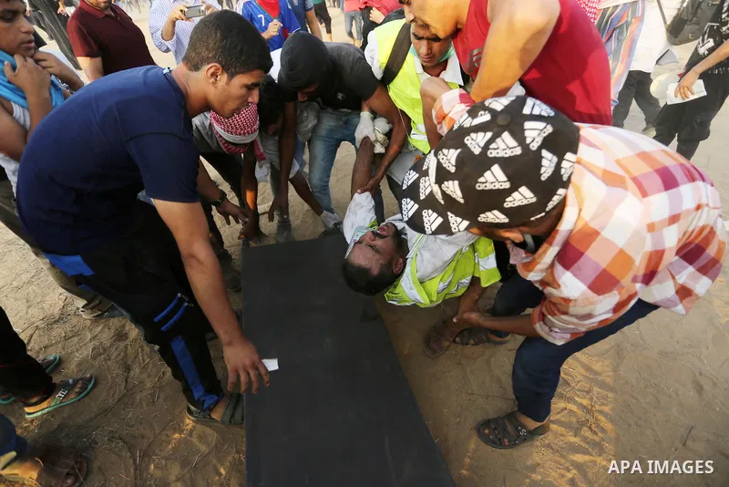 A wounded Palestinian paramedic is evacuated during clashes with Israeli troops in tents protest where Palestinians demand the right to return to their homeland at the Israel-Gaza border, in Khan Younis in the southern o...