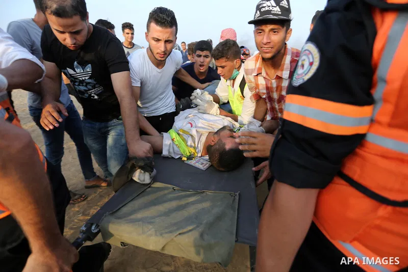 A wounded Palestinian paramedic is evacuated during clashes with Israeli troops in tents protest where Palestinians demand the right to return to their homeland at the Israel-Gaza border, in Khan Younis in the southern o...