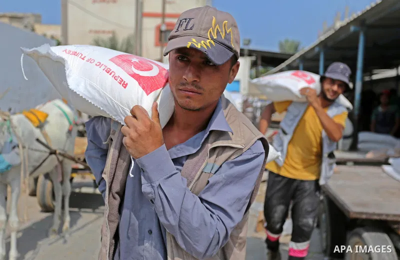 A Palestinian man carries a sack of flour at an aid distribution center run by United Nations Relief and Works Agency (UNRWA) in Deir al-Balah in the center of Gaza Strip on September 1, 2018. The United States on Friday...