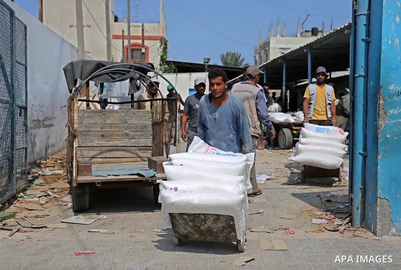 A Palestinian man pushes a cart loaded with sacks of flour at an aid distribution center run by United Nations Relief and Works Agency (UNRWA) in Deir al-Balah in the center of Gaza Strip on September 1, 2018. The United...