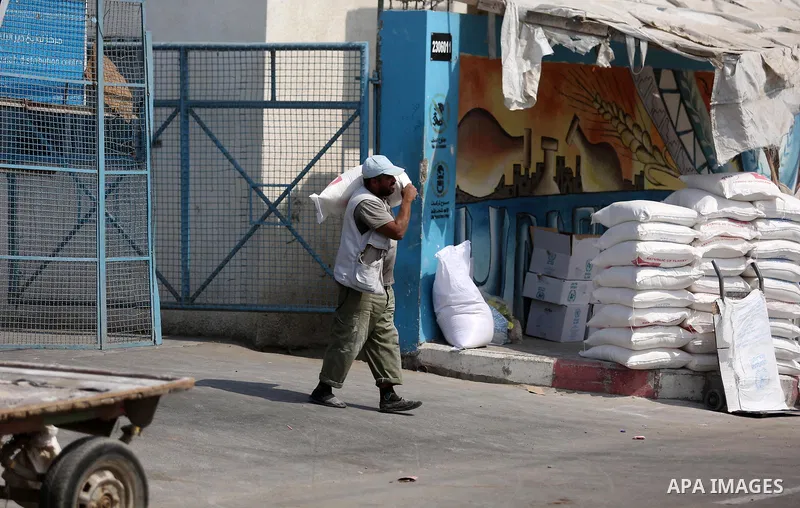 A Palestinian man carries a sack of flour at an aid distribution center run by United Nations Relief and Works Agency (UNRWA) in Deir al-Balah in the center of Gaza Strip on September 1, 2018. The United States on Friday...