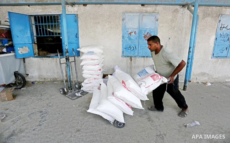 A Palestinian man pushes a cart loaded with sacks of flour at an aid distribution center run by United Nations Relief and Works Agency (UNRWA) in Deir al-Balah in the center of Gaza Strip on September 1, 2018. The United...