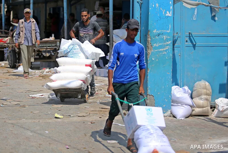 A Palestinian man pushes a cart loaded with sacks of flour at an aid distribution center run by United Nations Relief and Works Agency (UNRWA) in Deir al-Balah in the center of Gaza Strip on September 1, 2018. The United...