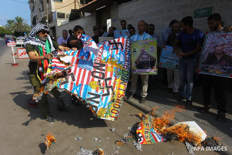Palestinians burn an Israeli, British and U.S. flags during a protest to show solidarity with Palestinian prisoners held in Israeli jails, in front of Red cross office in Gaza city on Sept. 03, 2018. Photo by Mahmoud Ajo...
