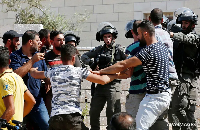 Israeli border policemen stand guard as Israeli bulldozer demolishes four houses owned by Palestinian families which Israeli authorities said it was built without a permit, in the West Bank village of Walajeh, near Bethl...