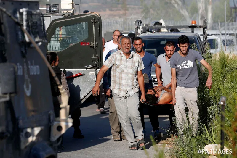 Palestinians carry wounded man during clashes with Israeli border policemen where Israeli bulldozer demolishes four houses owned by Palestinian families which Israeli authorities said it was built without a permit, in th...