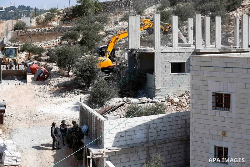Israeli border policemen stand guard as Israeli bulldozer demolishes four houses owned by Palestinian families which Israeli authorities said it was built without a permit, in the West Bank village of Walajeh, near Bethl...