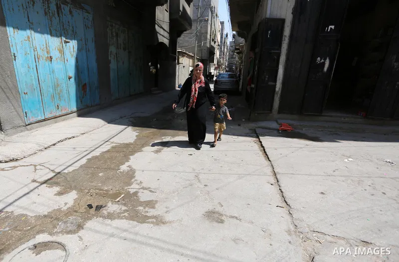 A Palestinian refugee woman walks with her son in a street at Al-Shati refugee camp, in Gaza City on September 3, 2018. The United States halted all funding to United Nations' agency that helps Palestinian refugees. Stat...