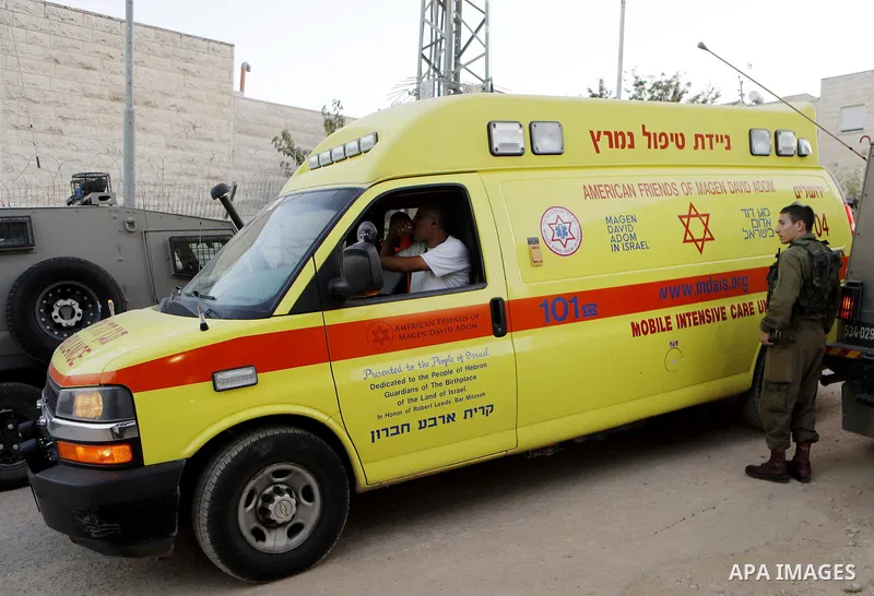 Israeli soldiers gather around an ambulance at the scene where a Palestinian, who according to the Israeli military attempted to stab a soldier, was shot dead, near a check point of the Israeli settlement of Kiryat Arba...