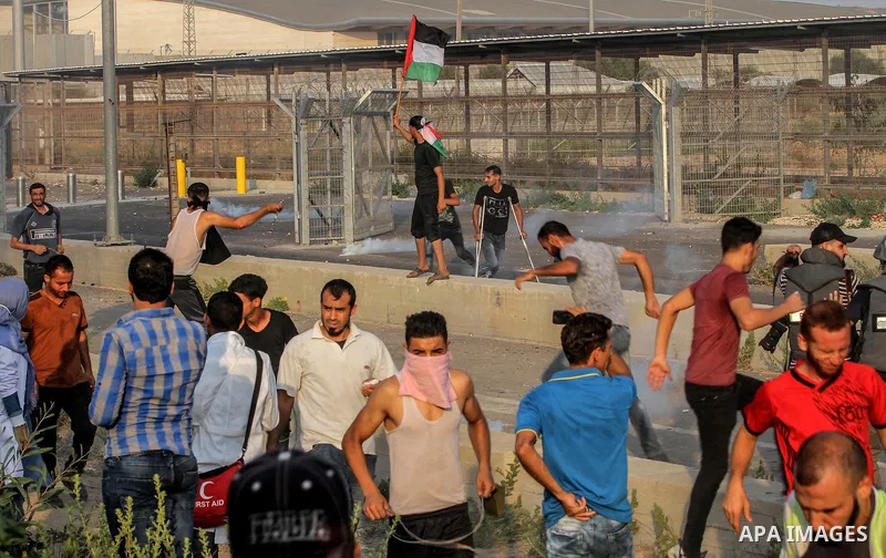 Palestinians gather during clashes with Israeli troops following a protest against the United States decision to stop funding and backing the United Nations agency for Palestinian refugees (UNRWA) at the Erez crossing wi...