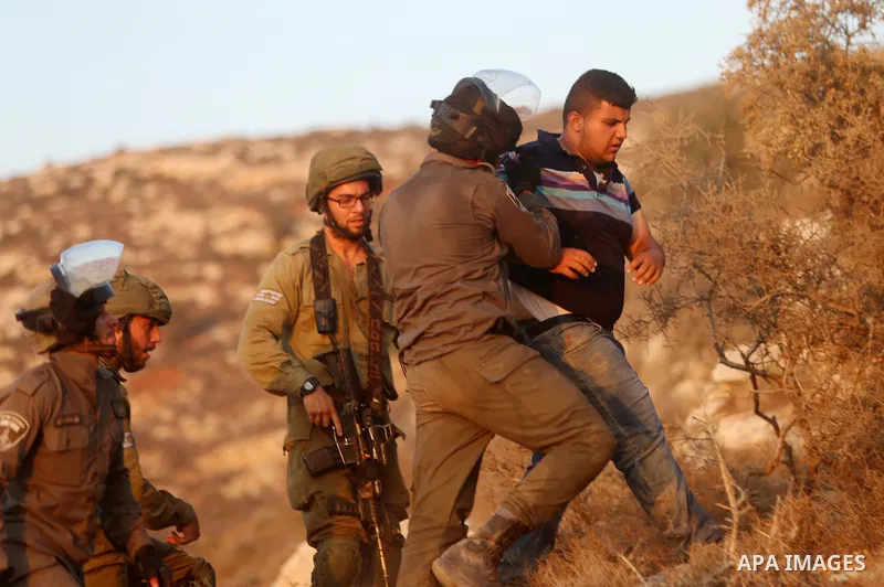 Israeli troops detain a Palestinian protester during a protest against Israeli settlement in the village of Ras Karkar, near the West Bank city of Ramallah on September 4, 2018. Photo by Shadi Hatem