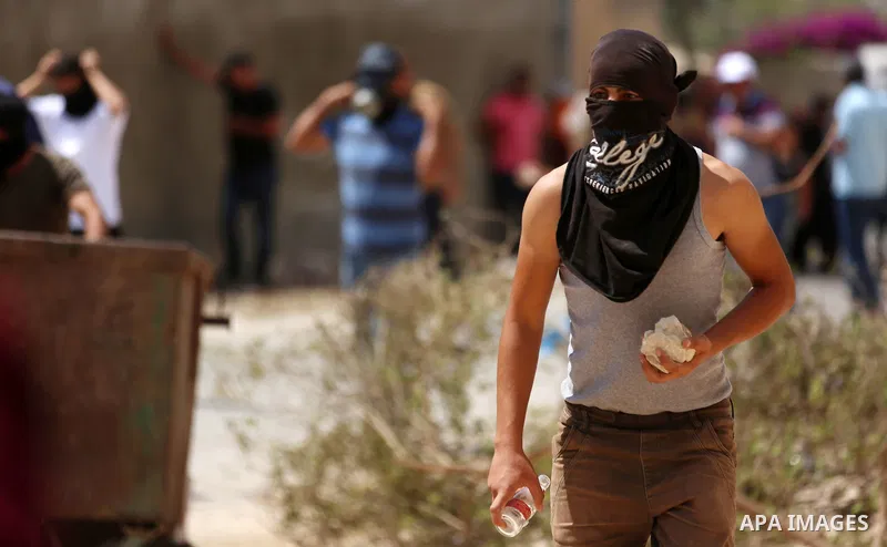 A Palestinian protester hurls stones towards Israeli forces during clashes following a weekly demonstration against the expropriation of Palestinian land by Israel in the village of Kfar Qaddum, near the West Bank city o...