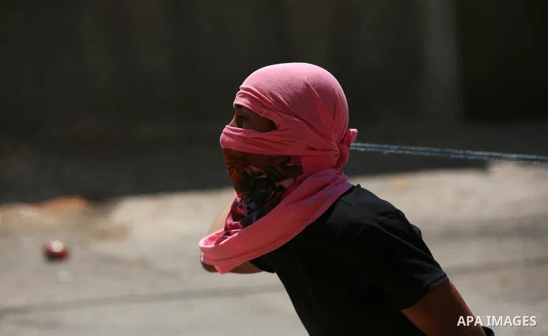 A Palestinian protester uses a slingshot to hurl stones towards Israeli forces during clashes following a weekly demonstration against the expropriation of Palestinian land by Israel in the village of Kfar Qaddum, near t...
