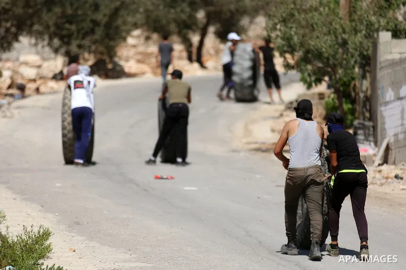 Palestinian protesters move tires during clashes with Israeli forces following a weekly demonstration against the expropriation of Palestinian land by Israel in the village of Kfar Qaddum, near the West Bank city of Nabl...
