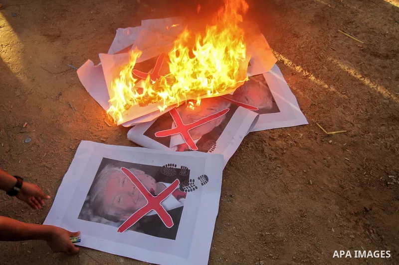 Palestinian protesters burn posters depicting US President Donald Trump during clashes with Israeli troops in tents protest where Palestinians demand the right to return to their homeland at the Israel-Gaza border, in ea...