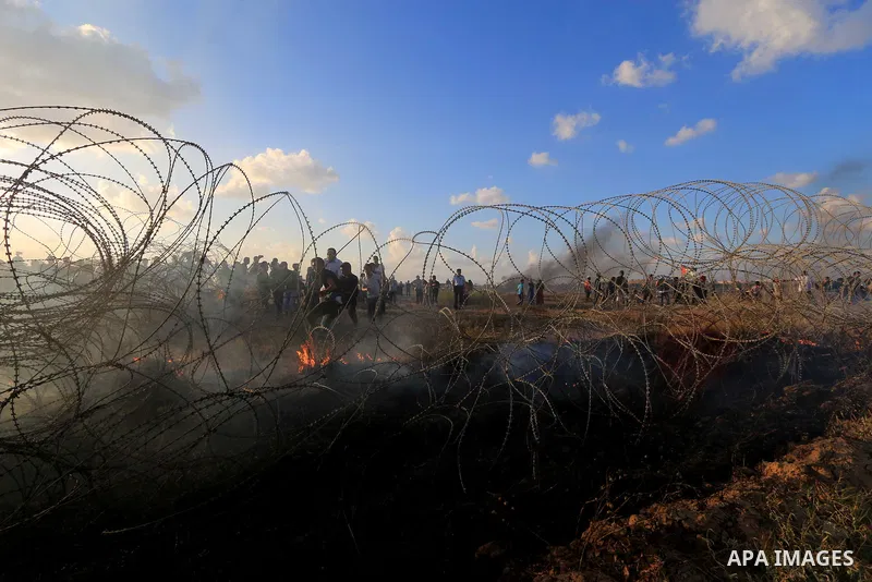 Palestinian protesters gather during clashes with Israeli troops in tents protest where Palestinians demand the right to return to their homeland at the Israel-Gaza border, in Al-Bureij in the center of Gaza Strip on Sep...