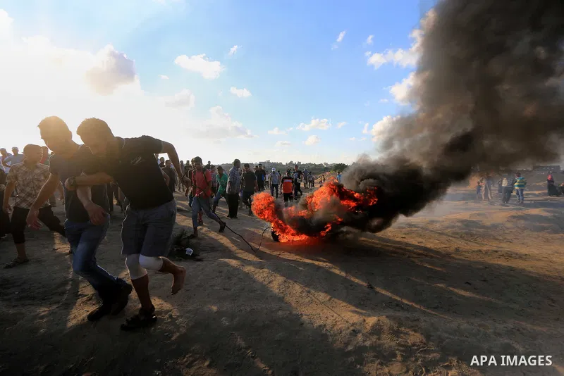 Palestinian protesters gather during clashes with Israeli troops in tents protest where Palestinians demand the right to return to their homeland at the Israel-Gaza border, in Al-Bureij in the center of Gaza Strip on Sep...