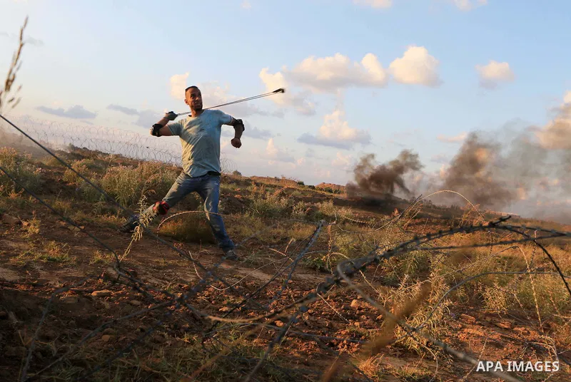 Palestinian protesters gather during clashes with Israeli troops in tents protest where Palestinians demand the right to return to their homeland at the Israel-Gaza border, in Al-Bureij in the center of Gaza Strip on Sep...