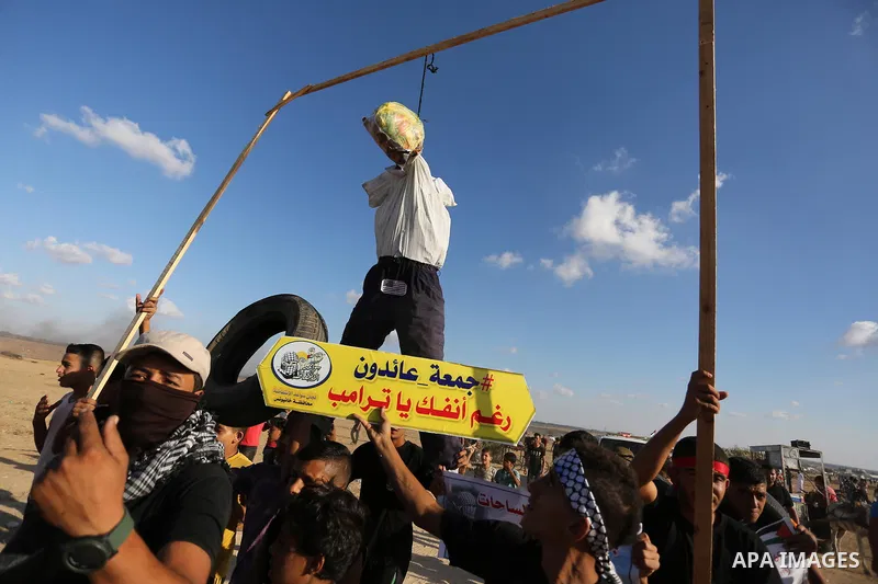 Palestinian protesters hang a doll wearing a mask depicting US President Donald Trump's face during clashes with Israeli troops in tents protest where Palestinians demand the right to return to their homeland at the Isra...