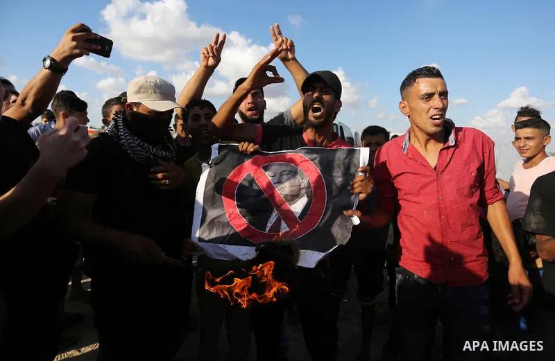 Palestinian protesters burn posters depicting US President Donald Trump during clashes with Israeli troops in tents protest where Palestinians demand the right to return to their homeland at the Israel-Gaza border, in Kh...