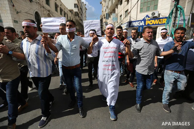 Palestinian graduates hold placards during a protest to demand their rights, outside the Ministry of Labor headquarters in Gaza city on September 9, 2018. Photo by Ashraf Amra