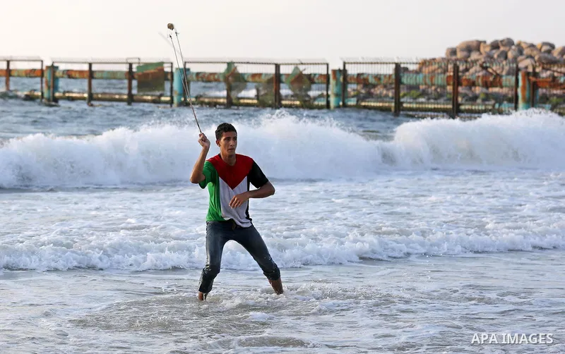 A Palestinian protester uses a slingshot to hurl stones towards Israeli troops during a demonstration against the Israeli blockade on Gaza Strip, along the Gaza sea barrier on the maritime border with Israel near Kibbutz...