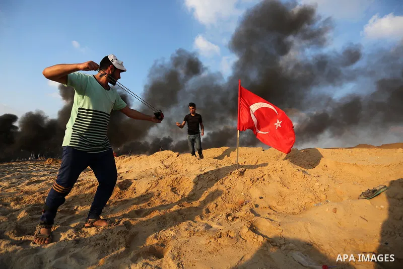 A Palestinian protester uses a slingshot to hurl stones towards Israeli troops during a demonstration against the Israeli blockade on Gaza Strip, along the Gaza sea barrier on the maritime border with Israel near Kibbutz...