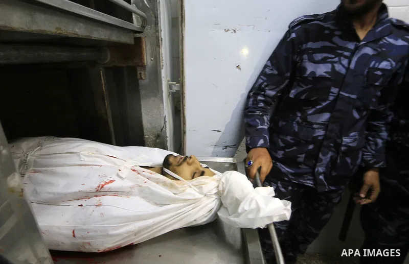 Palestinian policemen gather around the body of Palestinian Mohammed Shaqoura, 21, who was shot dead by Israeli troops during clashes in tents protest at the Israel-Gaza border, at morgue in a hospital in Deir al-Balah i...
