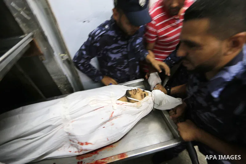 Palestinian policemen gather around the body of Palestinian Mohammed Shaqoura, 21, who was shot dead by Israeli troops during clashes in tents protest at the Israel-Gaza border, at morgue in a hospital in Deir al-Balah i...