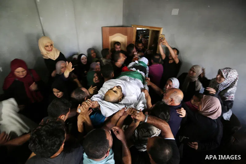 Mourners carry the body of Palestinian Mohammed Shaqoura, 21, who was shot dead by Israeli troops during clashes in tents protest at the Israel-Gaza border, during his funeral in al-Maghazi in the center of Gaza Strip on...