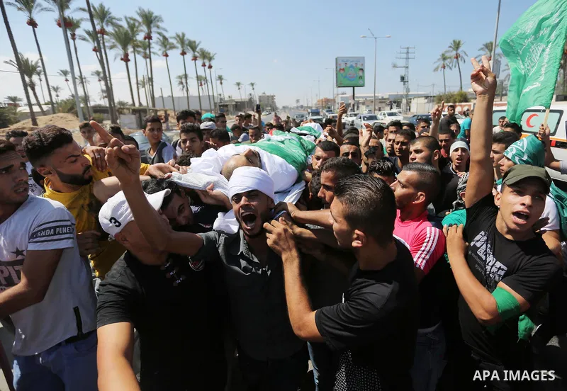 Mourners carry the body of Palestinian Mohammed Shaqoura, 21, who was shot dead by Israeli troops during clashes in tents protest at the Israel-Gaza border, during his funeral in al-Maghazi in the center of Gaza Strip on...