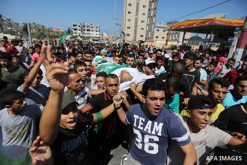 Mourners carry the body of Palestinian Mohammed Shaqoura, 21, who was shot dead by Israeli troops during clashes in tents protest at the Israel-Gaza border, during his funeral in al-Maghazi in the center of Gaza Strip on...