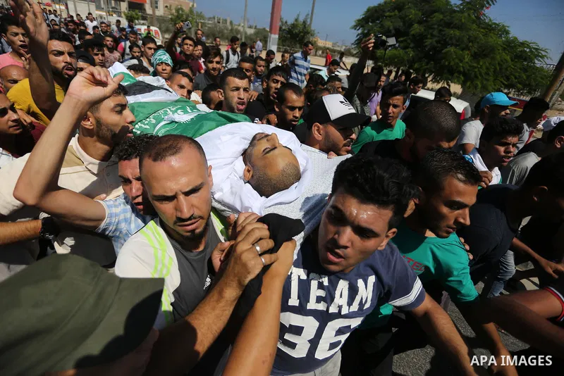 Mourners carry the body of Palestinian Mohammed Shaqoura, 21, who was shot dead by Israeli troops during clashes in tents protest at the Israel-Gaza border, during his funeral in al-Maghazi in the center of Gaza Strip on...