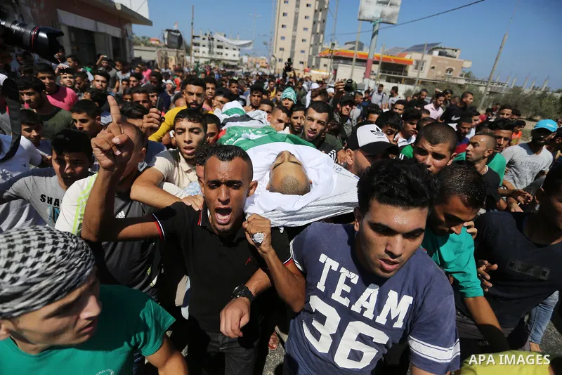 Mourners carry the body of Palestinian Mohammed Shaqoura, 21, who was shot dead by Israeli troops during clashes in tents protest at the Israel-Gaza border, during his funeral in al-Maghazi in the center of Gaza Strip on...