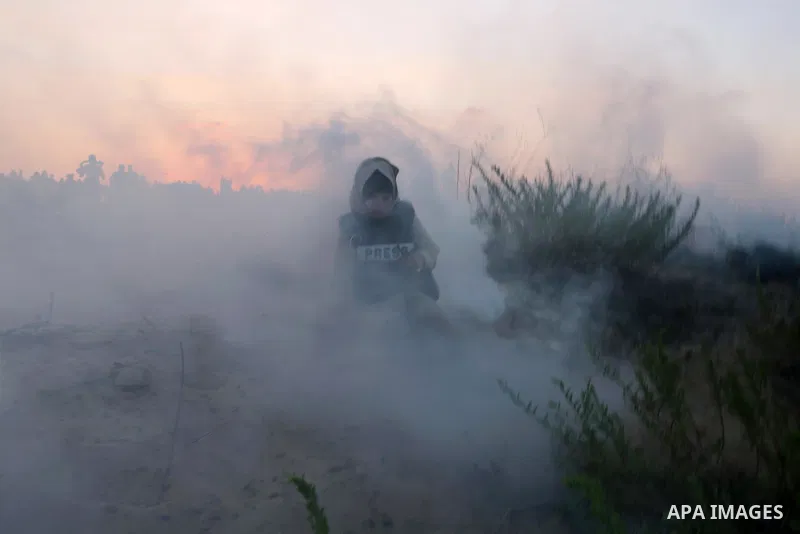 A Palestinian female journalist reacts to tear gas fired by Israeli troops during a demonstration against the Israeli blockade on Gaza Strip, along the Gaza sea barrier on the maritime border with Israel near Kibbutz Zik...