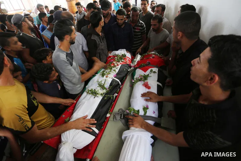 Relatives of Palestinians Naji Abu Assi and Alaa Abu Assi who were killed in an Israeli air strike at the Israel-Gaza border, mourn over their bodies during their funeral in Khan Younis in the southern Gaza Strip on Sept...