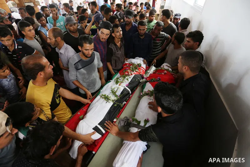Relatives of Palestinians Naji Abu Assi and Alaa Abu Assi who were killed in an Israeli air strike at the Israel-Gaza border, mourn over their bodies during their funeral in Khan Younis in the southern Gaza Strip on Sept...