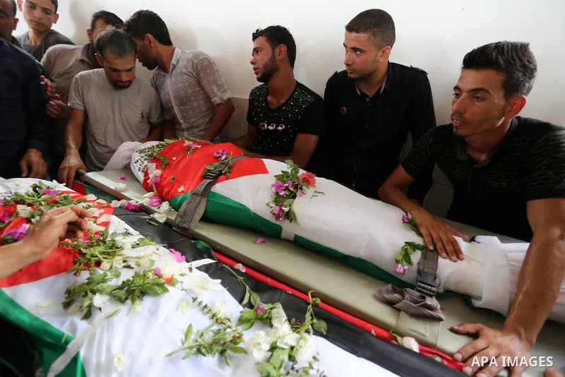 Relatives of Palestinians Naji Abu Assi and Alaa Abu Assi who were killed in an Israeli air strike at the Israel-Gaza border, mourn over their bodies during their funeral in Khan Younis in the southern Gaza Strip on Sept...