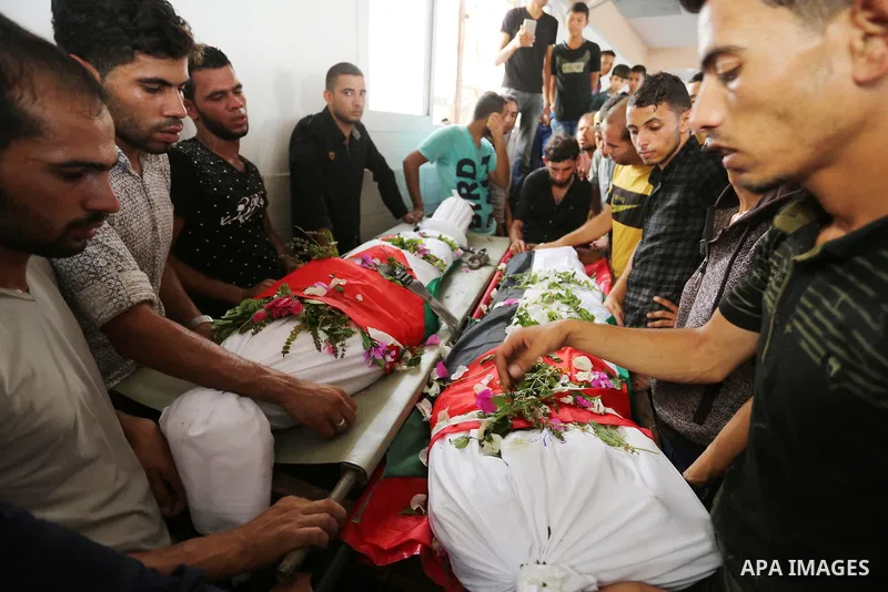 Relatives of Palestinians Naji Abu Assi and Alaa Abu Assi who were killed in an Israeli air strike at the Israel-Gaza border, mourn over their bodies during their funeral in Khan Younis in the southern Gaza Strip on Sept...