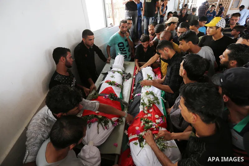Relatives of Palestinians Naji Abu Assi and Alaa Abu Assi who were killed in an Israeli air strike at the Israel-Gaza border, mourn over their bodies during their funeral in Khan Younis in the southern Gaza Strip on Sept...