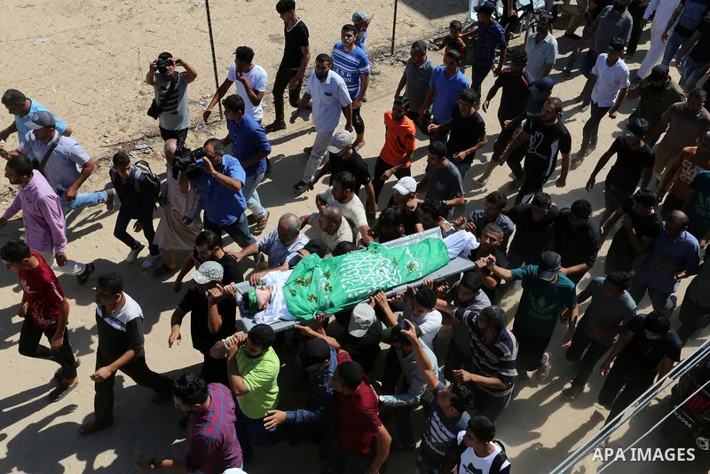 Mourners carry the body of Palestinian Mo'men Abu Eyada 15, who was shot dead by Israeli troops during clashes in tents protest at the Israel-Gaza border, during his funeral in Rafah in the southern Gaza Strip on Septemb...