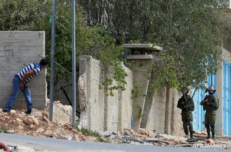 A Palestinian protester hurls stones towards Israeli forces during clashes following a weekly demonstration against the expropriation of Palestinian land by Israel in the village of Kfar Qaddum, near the West Bank city o...