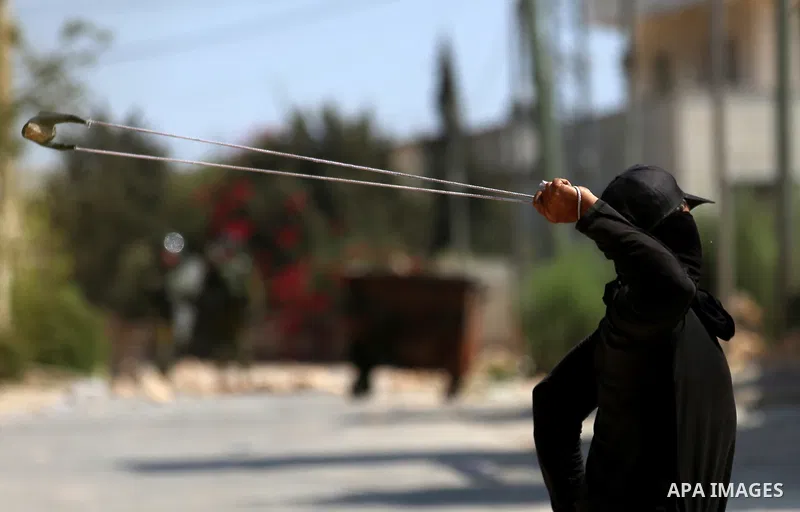 A Palestinian protester uses a slingshot to hurl stones towards Israeli forces during clashes following a weekly demonstration against the expropriation of Palestinian land by Israel in the village of Kfar Qaddum, near t...