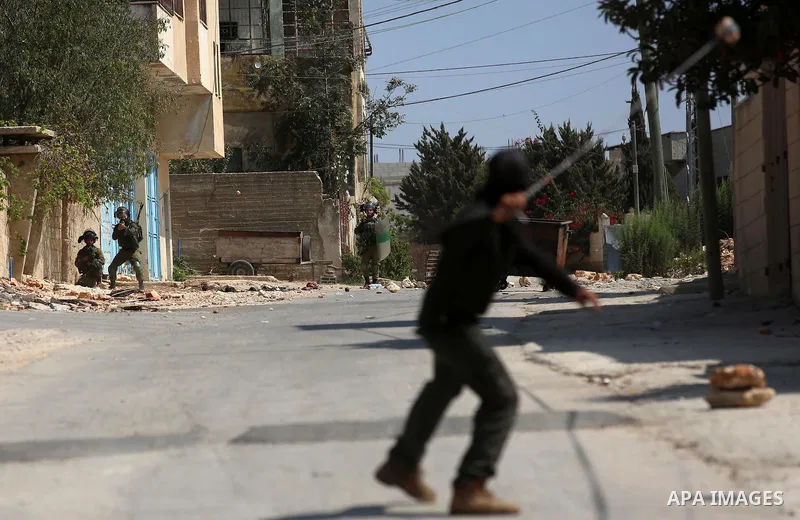 A Palestinian protester uses a slingshot to hurl stones towards Israeli forces during clashes following a weekly demonstration against the expropriation of Palestinian land by Israel in the village of Kfar Qaddum, near t...