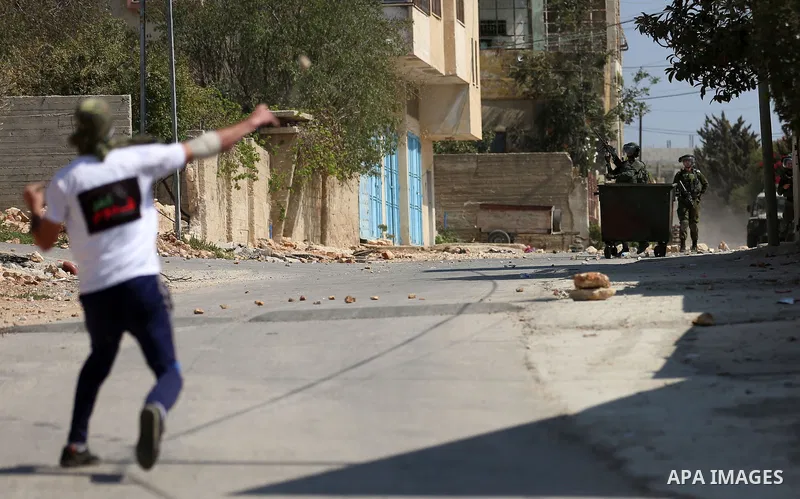 A Palestinian protester hurls stones towards Israeli forces during clashes following a weekly demonstration against the expropriation of Palestinian land by Israel in the village of Kfar Qaddum, near the West Bank city o...